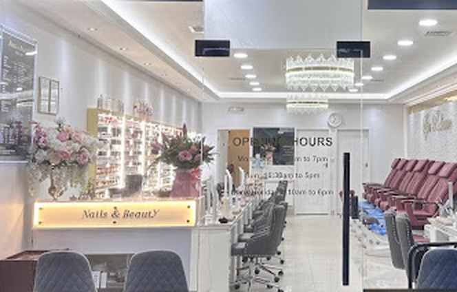 Inside Nails & Beauty on Well Hall Road: the lit reception desk, pink flowers, polish wall and chandelier